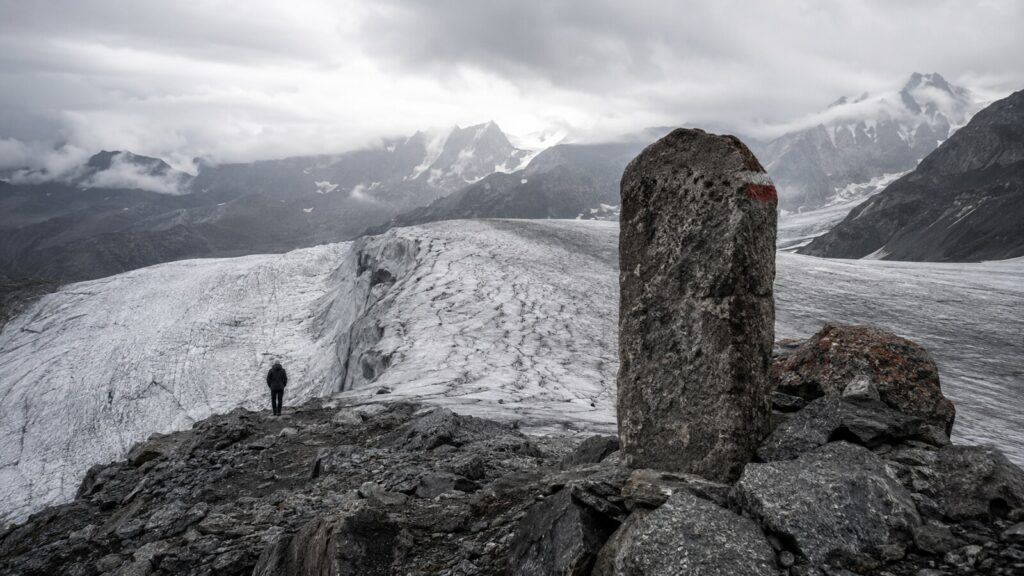 Grenzstein vor einem schmelzenden Alpengletscher