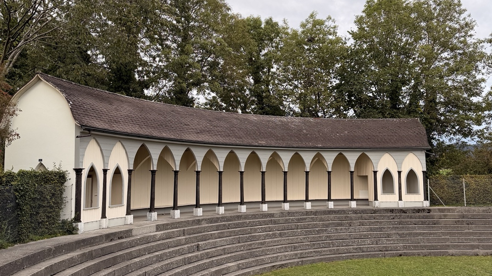 Historischer Badepavillon Römerbedli in Hofwil bei Münchenbuchsee mit Spitzbogenarkaden und den gebogenen Stufen des trockenen Badeweihers.